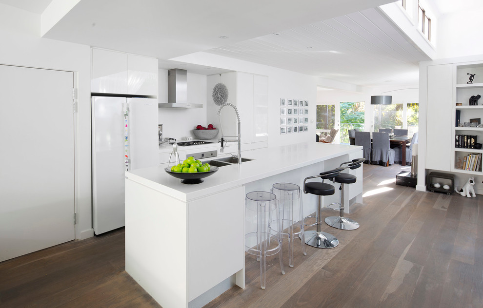 Источник вдохновения для домашнего уюта: параллельная кухня-гостиная в современном стиле с двойной мойкой, плоскими фасадами, белыми фасадами и белой техникой