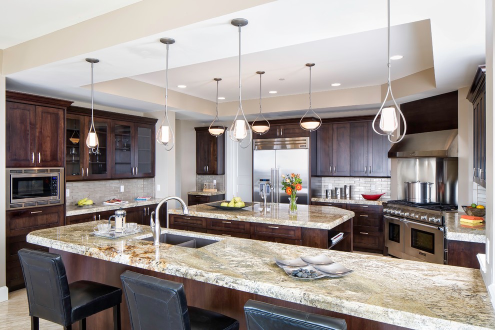 Example of a large classic marble floor kitchen design in Denver with a double-bowl sink, recessed-panel cabinets, dark wood cabinets, granite countertops, beige backsplash, glass tile backsplash, stainless steel appliances and an island