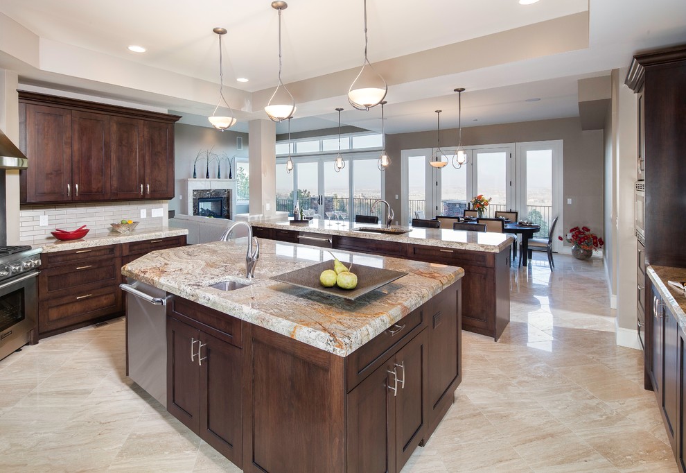 Imagen de cocina comedor contemporánea grande con fregadero de doble seno, armarios con paneles empotrados, puertas de armario de madera en tonos medios, encimera de granito, salpicadero blanco, salpicadero de azulejos de vidrio, electrodomésticos de acero inoxidable, suelo de travertino y dos o más islas