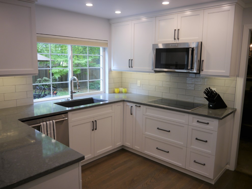 Idéer för stora vintage grått kök och matrum, med en undermonterad diskho, luckor med infälld panel, vita skåp, bänkskiva i kvarts, vitt stänkskydd, stänkskydd i keramik, rostfria vitvaror, mellanmörkt trägolv, en halv köksö och brunt golv