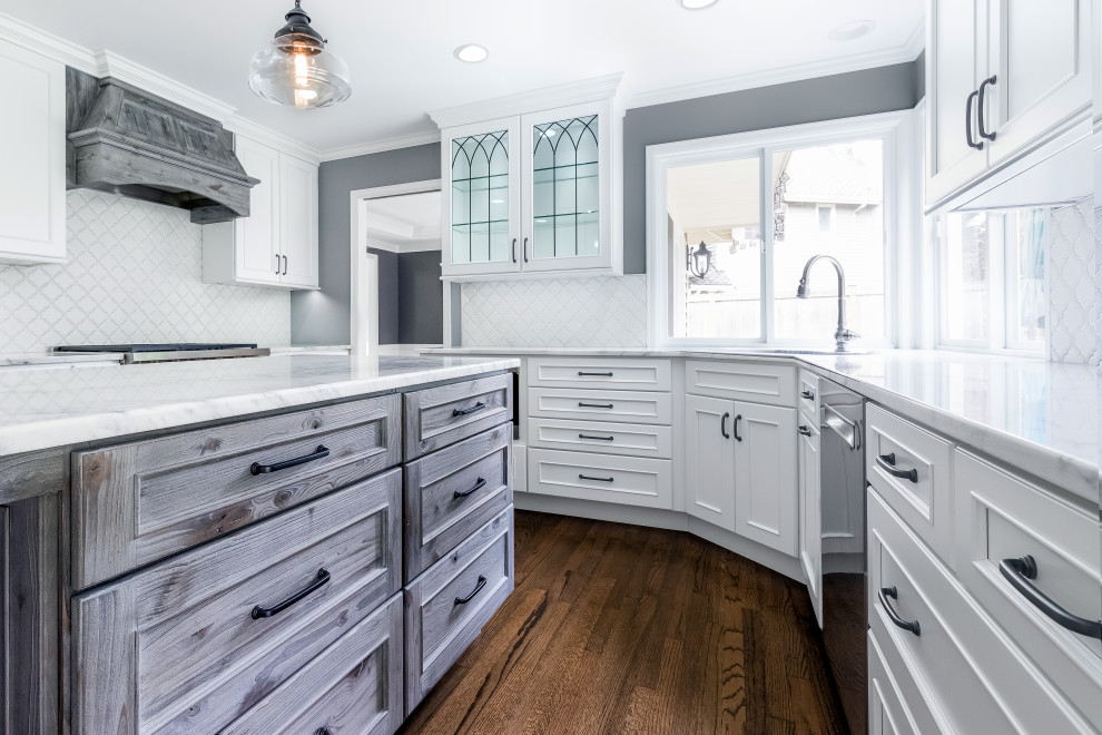 Bild på ett mellanstort vintage vit vitt kök, med en undermonterad diskho, luckor med infälld panel, vita skåp, bänkskiva i kvartsit, vitt stänkskydd, stänkskydd i porslinskakel, rostfria vitvaror, mörkt trägolv, en köksö och brunt golv