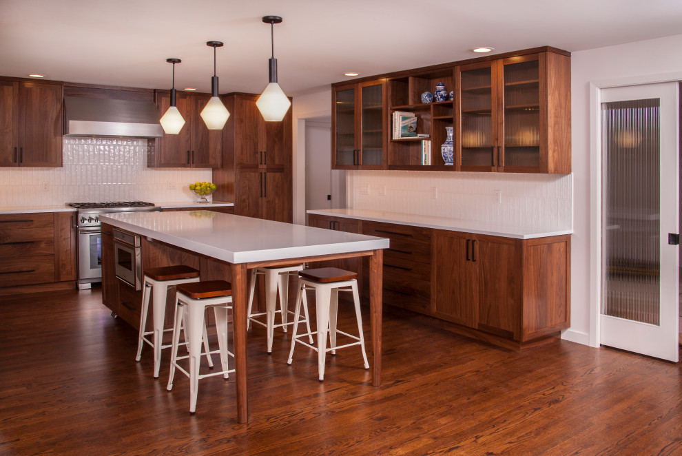 Mid-sized mid-century modern u-shaped dark wood floor and brown floor eat-in kitchen photo in Seattle with an undermount sink, recessed-panel cabinets, dark wood cabinets, quartz countertops, white backsplash, ceramic backsplash, stainless steel appliances, an island and white countertops