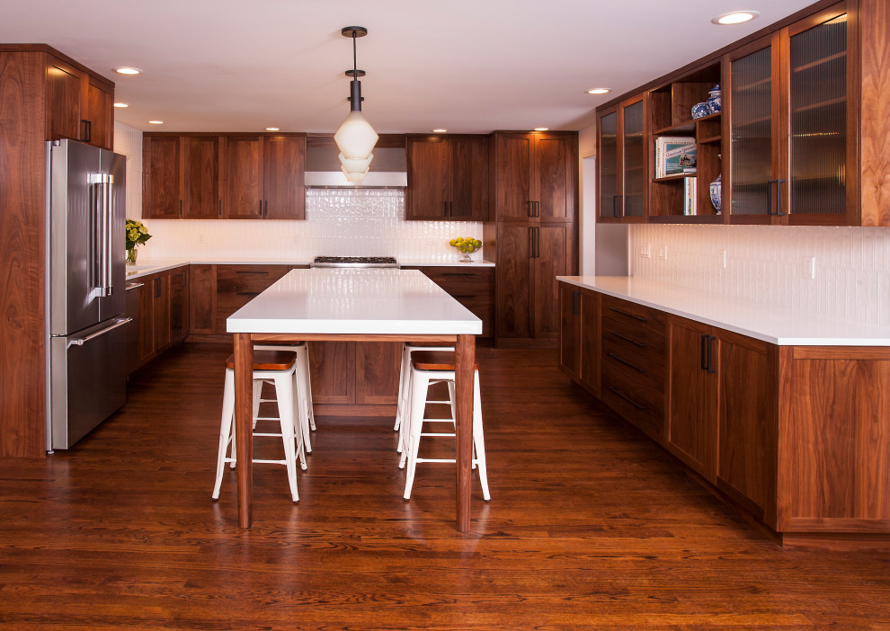 Example of a mid-sized 1950s u-shaped dark wood floor and brown floor eat-in kitchen design in Seattle with an undermount sink, recessed-panel cabinets, dark wood cabinets, quartz countertops, white backsplash, ceramic backsplash, stainless steel appliances, an island and white countertops