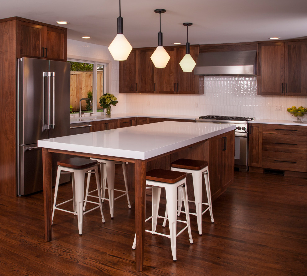 Exempel på ett mellanstort 60 tals vit vitt kök, med en undermonterad diskho, luckor med infälld panel, skåp i mörkt trä, bänkskiva i kvarts, vitt stänkskydd, stänkskydd i keramik, rostfria vitvaror, mörkt trägolv, en köksö och brunt golv