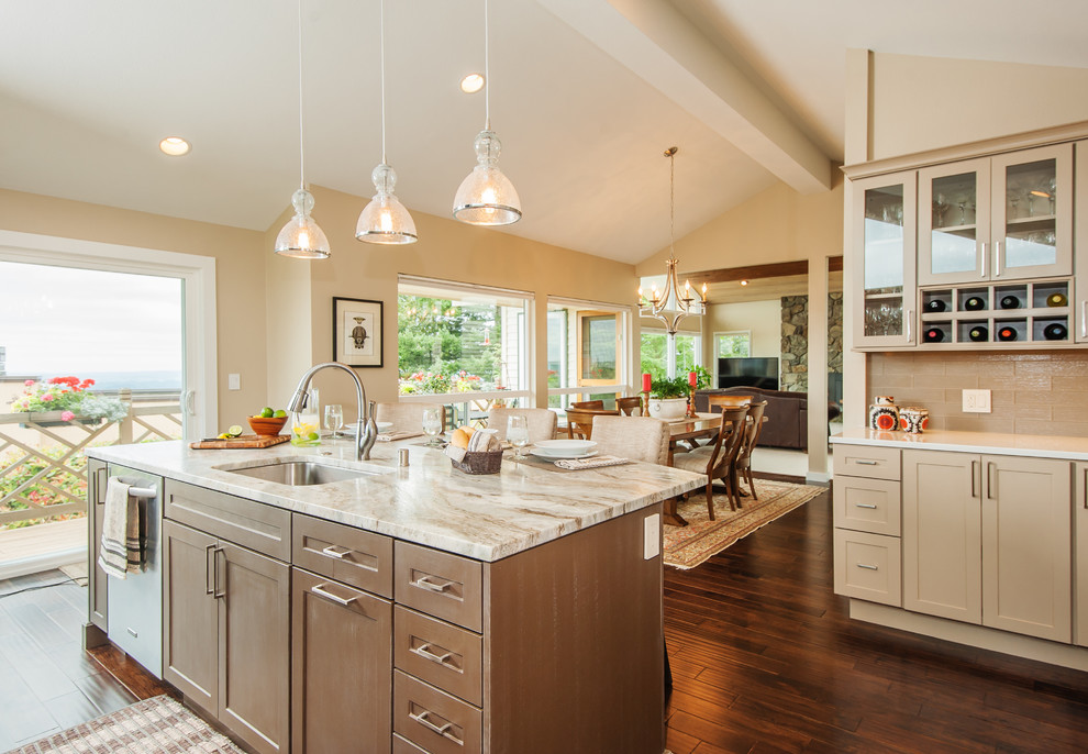 This is an example of a classic l-shaped open plan kitchen in Seattle with a submerged sink, shaker cabinets, beige cabinets, quartz worktops, stainless steel appliances, medium hardwood flooring, an island and brown floors.