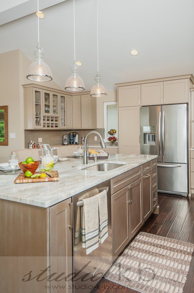 This is an example of a traditional l-shaped open plan kitchen in Seattle with a submerged sink, shaker cabinets, beige cabinets, quartz worktops, stainless steel appliances, medium hardwood flooring, an island and brown floors.