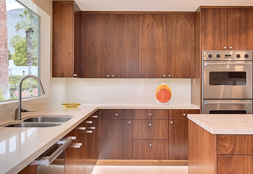 シアトルにある中くらいなコンテンポラリースタイルのおしゃれなキッチン (フラットパネル扉のキャビネット、ダブルシンク、中間色木目調キャビネット、クオーツストーンカウンター、白いキッチンパネル、ガラス板のキッチンパネル、シルバーの調理設備) の写真