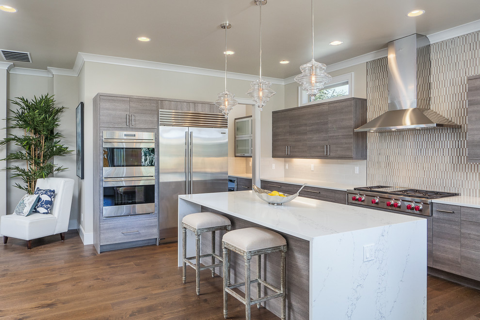 This is an example of a large contemporary l-shaped kitchen in Seattle with flat-panel cabinets, medium wood cabinets, marble worktops, metallic splashback, matchstick tiled splashback, stainless steel appliances, medium hardwood flooring and an island.
