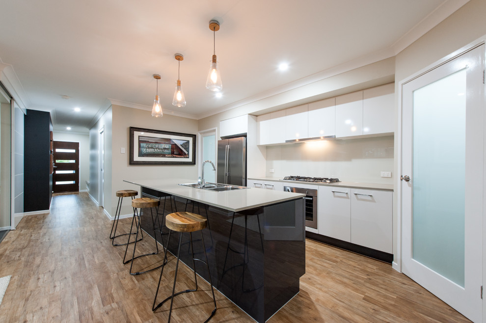 This is an example of a large contemporary kitchen/diner in Sunshine Coast with engineered stone countertops, white splashback, ceramic splashback, stainless steel appliances and an island.