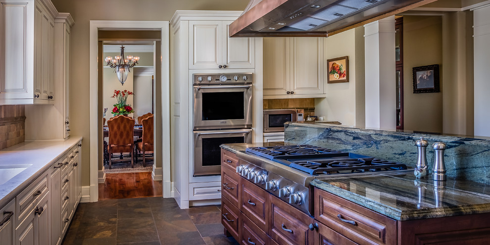 Exempel på ett stort, avskilt rustikt u-kök, med en undermonterad diskho, luckor med upphöjd panel, skåp i slitet trä, granitbänkskiva, flerfärgad stänkskydd, integrerade vitvaror, skiffergolv, en köksö och grönt golv