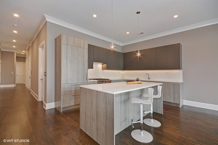 Open concept kitchen - large contemporary l-shaped medium tone wood floor open concept kitchen idea in Chicago with an undermount sink, flat-panel cabinets, beige cabinets, quartz countertops, beige backsplash, paneled appliances and an island