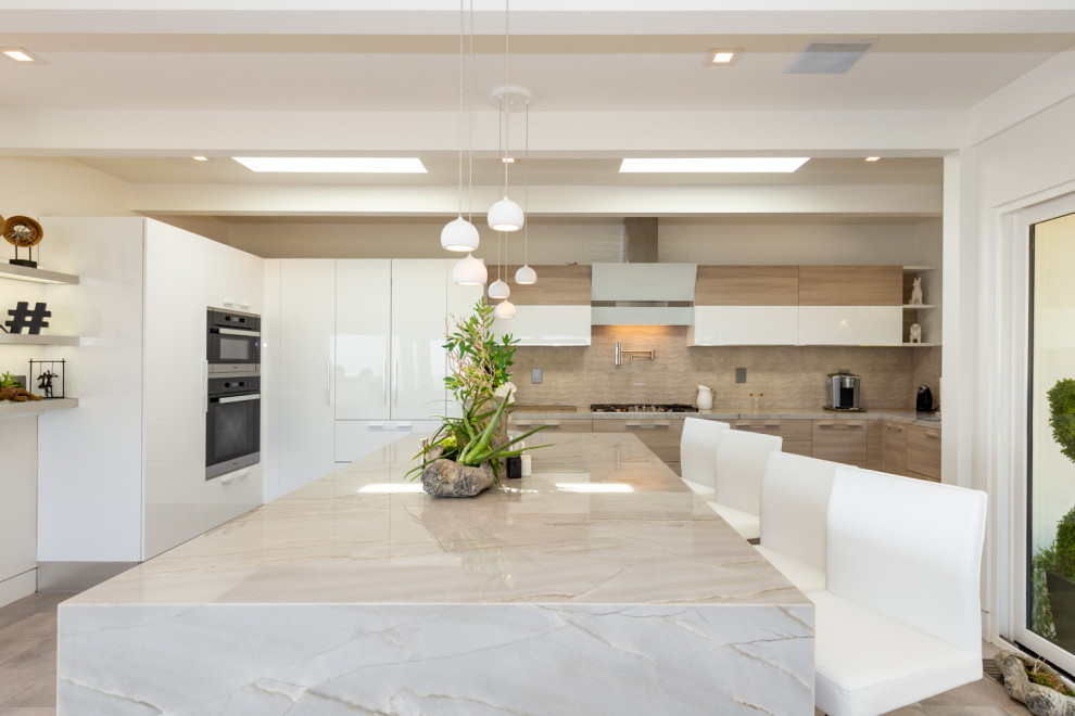 This is an example of a large contemporary l-shaped open plan kitchen in San Francisco with a submerged sink, flat-panel cabinets, light wood cabinets, granite worktops, brown splashback, glass tiled splashback, stainless steel appliances, an island and brown worktops.