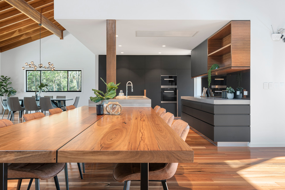 Zweizeilige, Große Moderne Wohnküche mit Rückwand aus Spiegelfliesen, braunem Holzboden, Kücheninsel und grauer Arbeitsplatte in Brisbane