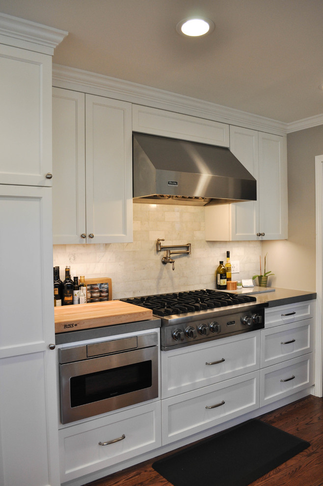 Exempel på ett mellanstort klassiskt kök, med en enkel diskho, luckor med infälld panel, vita skåp, bänkskiva i kvarts, vitt stänkskydd, stänkskydd i stenkakel, rostfria vitvaror och mellanmörkt trägolv