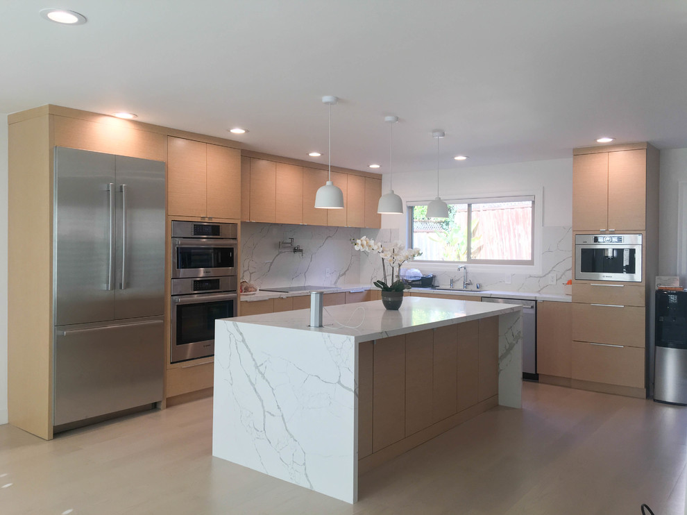 This is an example of a large modern l-shaped open plan kitchen in San Francisco with a submerged sink, flat-panel cabinets, beige cabinets, engineered stone countertops, white splashback, stone slab splashback, stainless steel appliances, light hardwood flooring, an island, beige floors and white worktops.