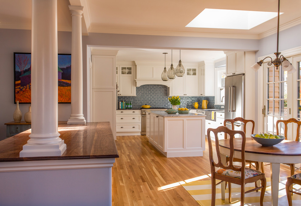 ボストンにある高級な広いヴィクトリアン調のおしゃれなキッチン (エプロンフロントシンク、シェーカースタイル扉のキャビネット、白いキャビネット、大理石カウンター、ガラスタイルのキッチンパネル、シルバーの調理設備、無垢フローリング、青いキッチンパネル) の写真