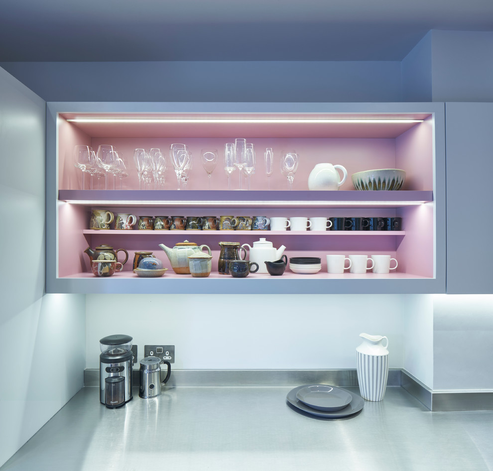 ロンドンにある高級な広いコンテンポラリースタイルのおしゃれなキッチン (フラットパネル扉のキャビネット、青いキャビネット、ステンレスカウンター、パネルと同色の調理設備、淡色無垢フローリング) の写真