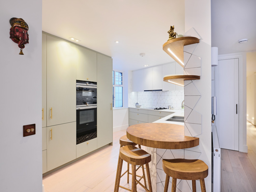 Design ideas for a medium sized contemporary l-shaped enclosed kitchen in London with a submerged sink, flat-panel cabinets, grey cabinets, composite countertops, white splashback, ceramic splashback, black appliances, no island, beige floors and white worktops.