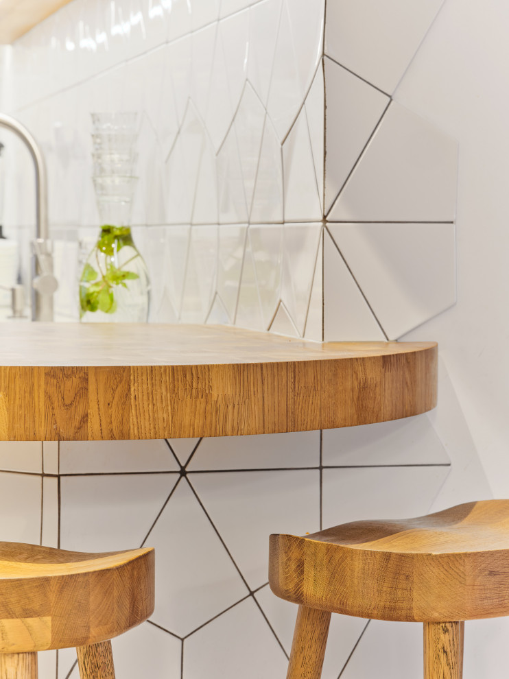 Photo of a medium sized contemporary l-shaped enclosed kitchen in London with a submerged sink, flat-panel cabinets, grey cabinets, composite countertops, white splashback, ceramic splashback, black appliances, light hardwood flooring, no island and yellow worktops.