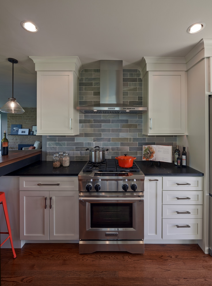 Mid-sized 1960s galley medium tone wood floor and brown floor eat-in kitchen photo in Seattle with shaker cabinets, white cabinets, soapstone countertops, green backsplash, stainless steel appliances and an island