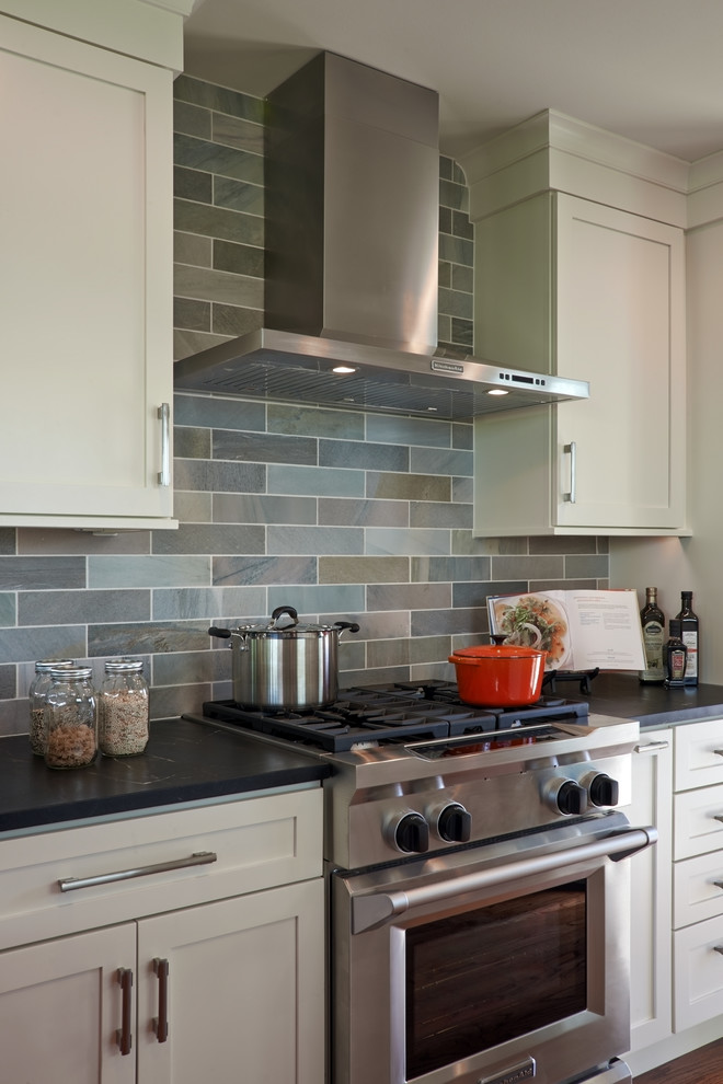 Immagine di una cucina minimalista di medie dimensioni con ante in stile shaker, ante bianche, top in saponaria, paraspruzzi verde, elettrodomestici in acciaio inossidabile, paraspruzzi in ardesia e pavimento marrone