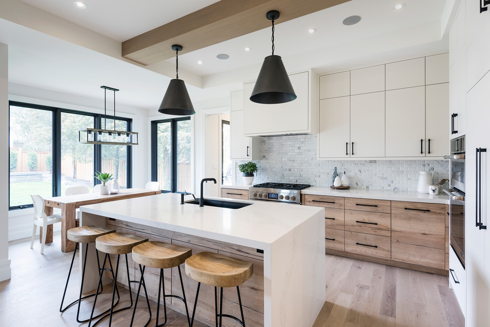 Klassische Wohnküche in L-Form mit flächenbündigen Schrankfronten, weißen Schränken, hellem Holzboden, Kücheninsel und braunem Boden in Toronto