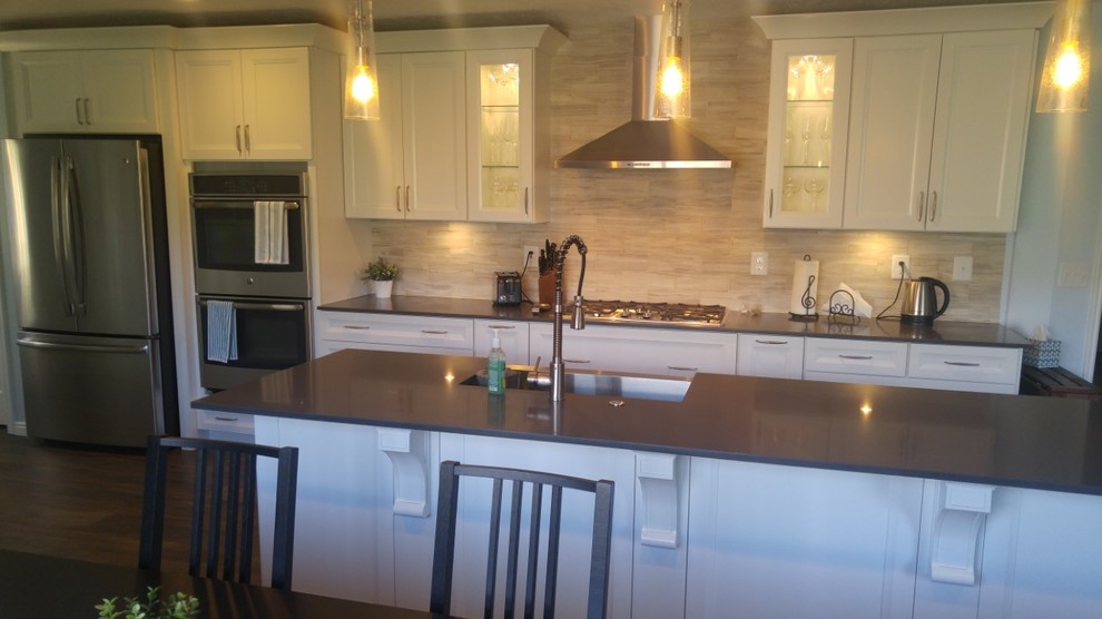 This is an example of a medium sized traditional galley kitchen/diner in Salt Lake City with a belfast sink, recessed-panel cabinets, white cabinets, engineered stone countertops, beige splashback, limestone splashback, stainless steel appliances, vinyl flooring, an island and grey floors.