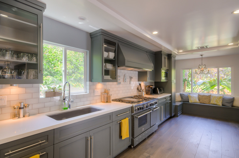 Example of a large transitional single-wall medium tone wood floor kitchen design in Los Angeles with an undermount sink, shaker cabinets, gray cabinets, white backsplash, subway tile backsplash and stainless steel appliances