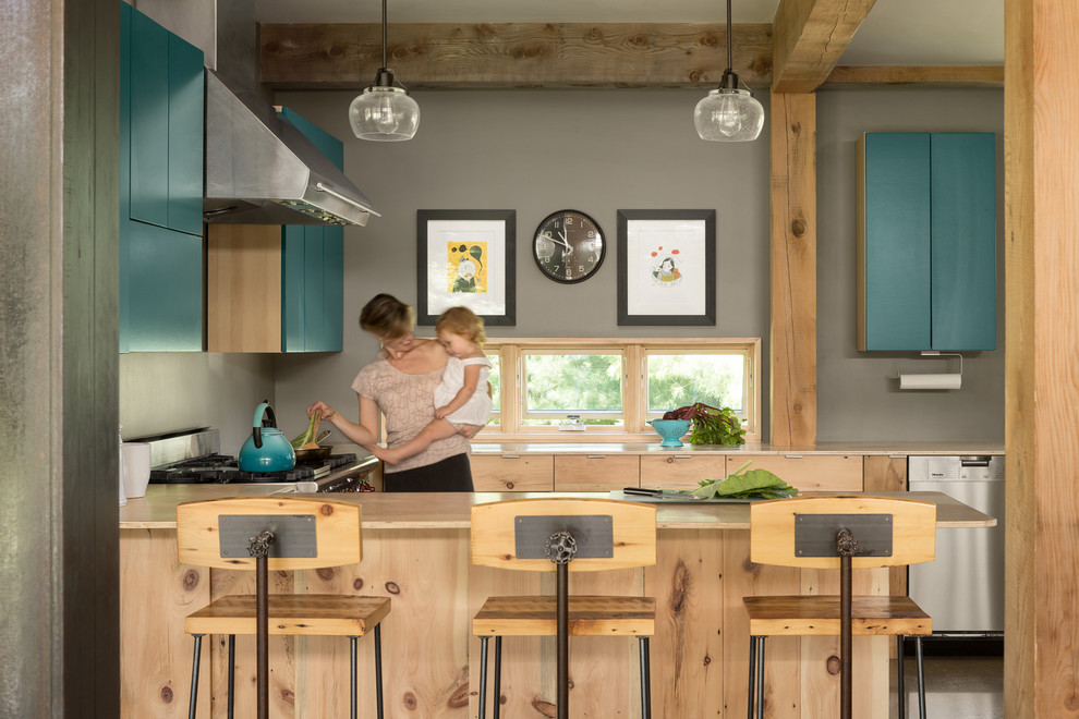 Cette photo montre une cuisine américaine chic avec un placard à porte plane, des portes de placard bleues, une crédence grise et une péninsule.