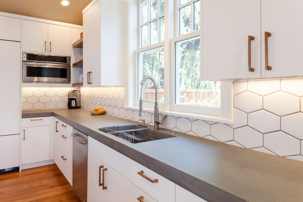 Idéer för att renovera ett mellanstort nordiskt grå grått kök, med en undermonterad diskho, släta luckor, vita skåp, bänkskiva i betong, vitt stänkskydd, stänkskydd i keramik, integrerade vitvaror, mellanmörkt trägolv, en köksö och brunt golv