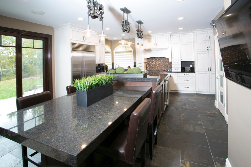 Inspiration for a large transitional galley slate floor open concept kitchen remodel in Edmonton with white cabinets, granite countertops, multicolored backsplash, terra-cotta backsplash, stainless steel appliances and an island