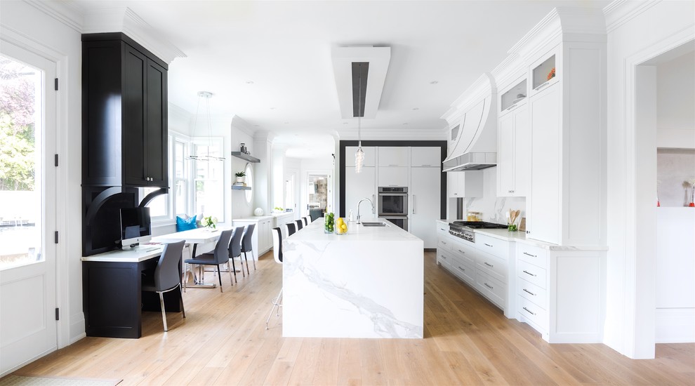 Example of a large trendy galley medium tone wood floor and brown floor open concept kitchen design in Toronto with an undermount sink, shaker cabinets, white cabinets, marble countertops, white backsplash, marble backsplash, stainless steel appliances and an island