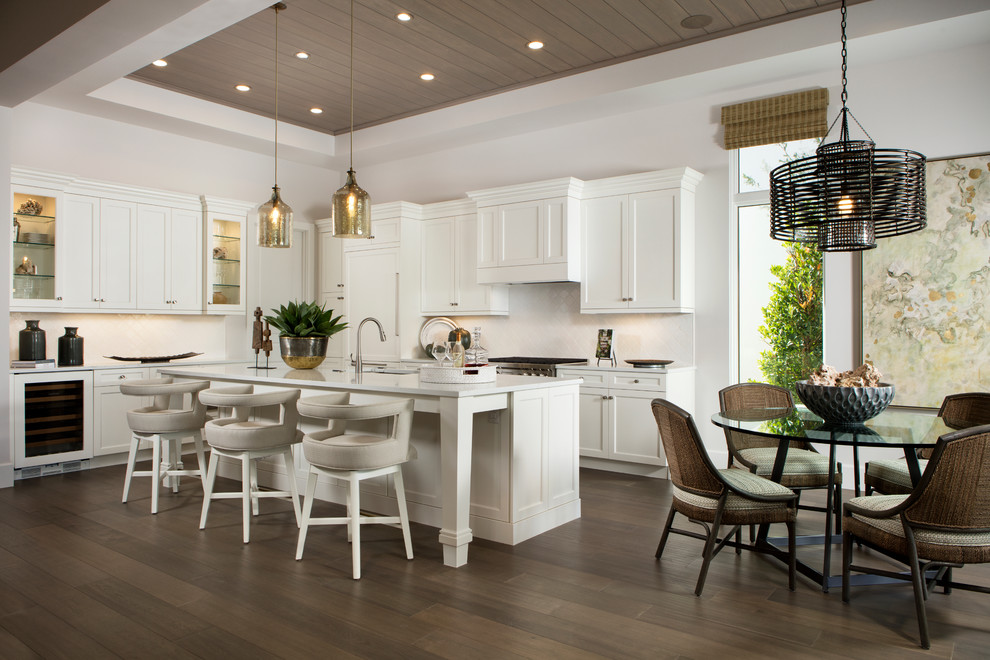 Beach style l-shaped dark wood floor and brown floor eat-in kitchen photo in Miami with shaker cabinets, white cabinets, white backsplash, an island and white countertops