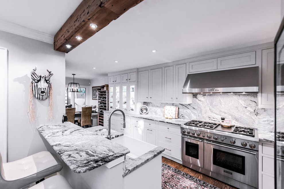 Inspiration for a large contemporary galley kitchen/diner in Charleston with a belfast sink, shaker cabinets, white cabinets, stone slab splashback, stainless steel appliances, medium hardwood flooring, a breakfast bar and grey splashback.