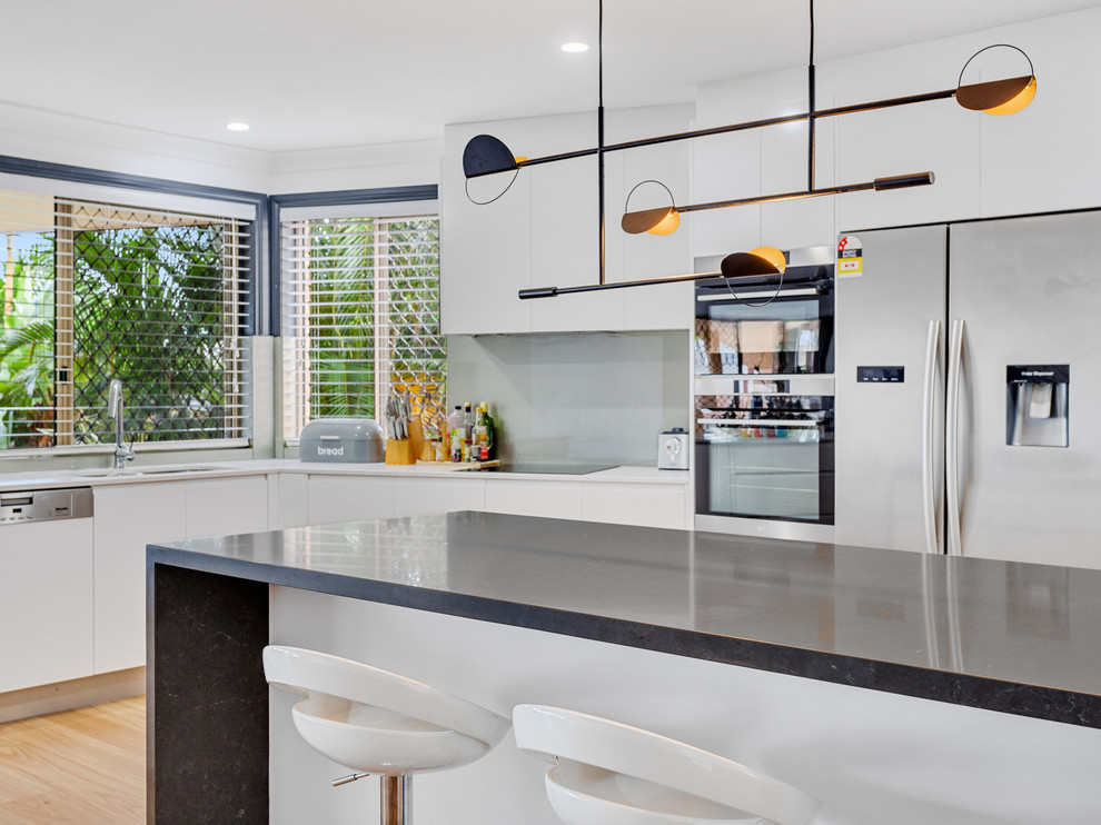 Inspiration for a large modern u-shaped open concept kitchen remodel in Gold Coast - Tweed with an undermount sink, flat-panel cabinets, white cabinets, quartz countertops, beige backsplash, glass sheet backsplash, stainless steel appliances, an island and brown countertops