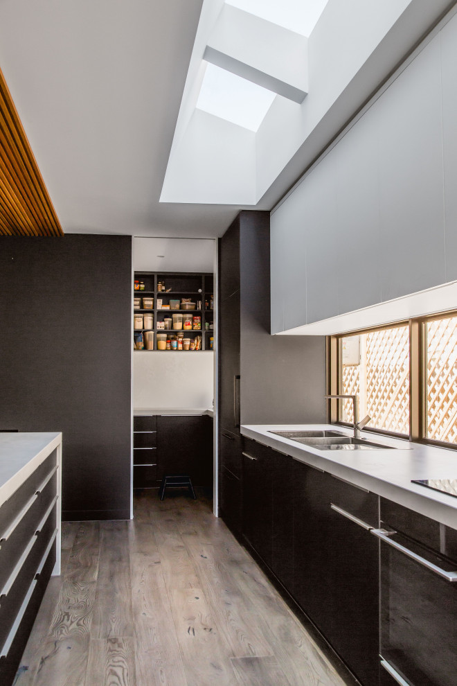 This is an example of a large contemporary u-shaped open plan kitchen in Melbourne with a double-bowl sink, recessed-panel cabinets, black cabinets, engineered stone countertops, dark hardwood flooring, an island, grey floors and grey worktops.