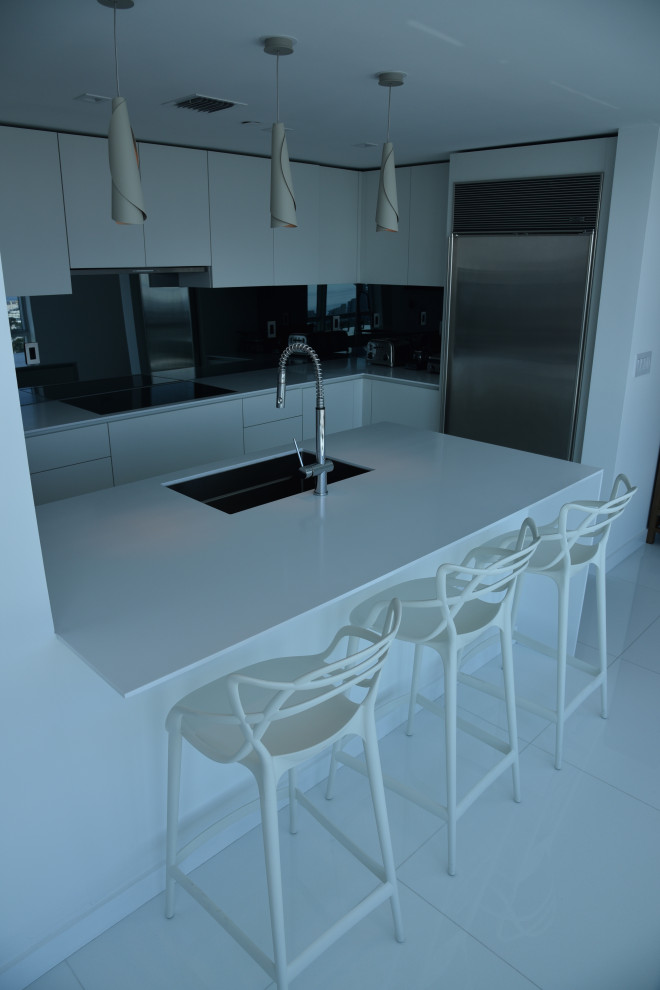 Exempel på ett mellanstort modernt vit vitt kök, med en nedsänkt diskho, släta luckor, vita skåp, bänkskiva i kvarts, vitt stänkskydd, glaspanel som stänkskydd, rostfria vitvaror, klinkergolv i porslin, en köksö och vitt golv