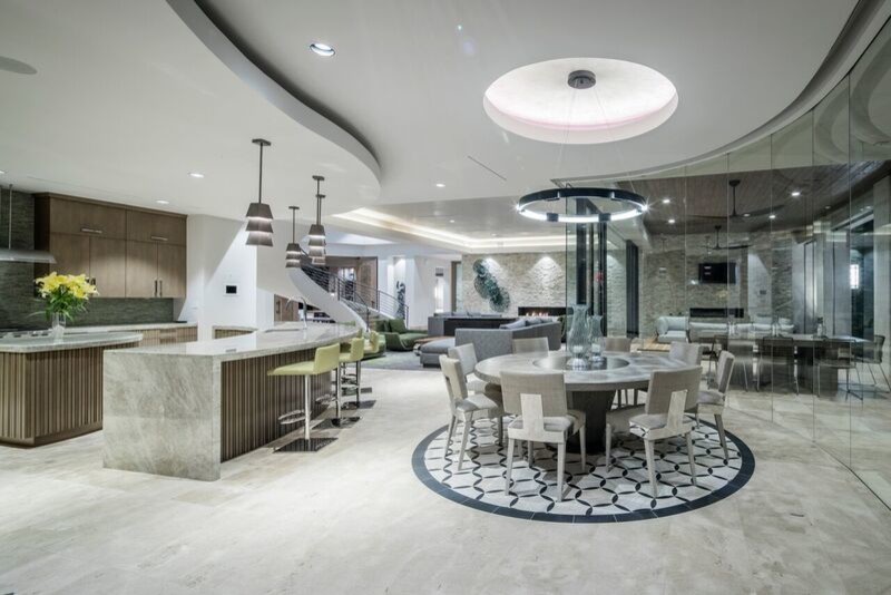 Expansive contemporary l-shaped open plan kitchen in Houston with a submerged sink, flat-panel cabinets, grey cabinets, granite worktops, blue splashback, glass tiled splashback, integrated appliances, marble flooring and multiple islands.