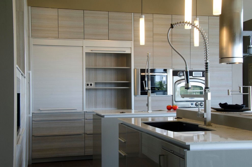 Modern inredning av ett stort kök, med en undermonterad diskho, släta luckor, grå skåp, bänkskiva i kvarts, brunt stänkskydd, stänkskydd i glaskakel, rostfria vitvaror och flera köksöar