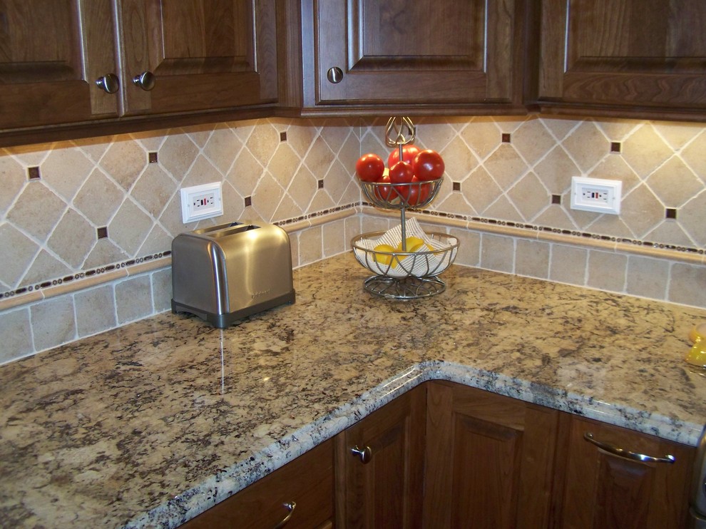 Foto di una cucina chic con lavello sottopiano, ante con bugna sagomata, ante in legno scuro, top in granito e elettrodomestici in acciaio inossidabile