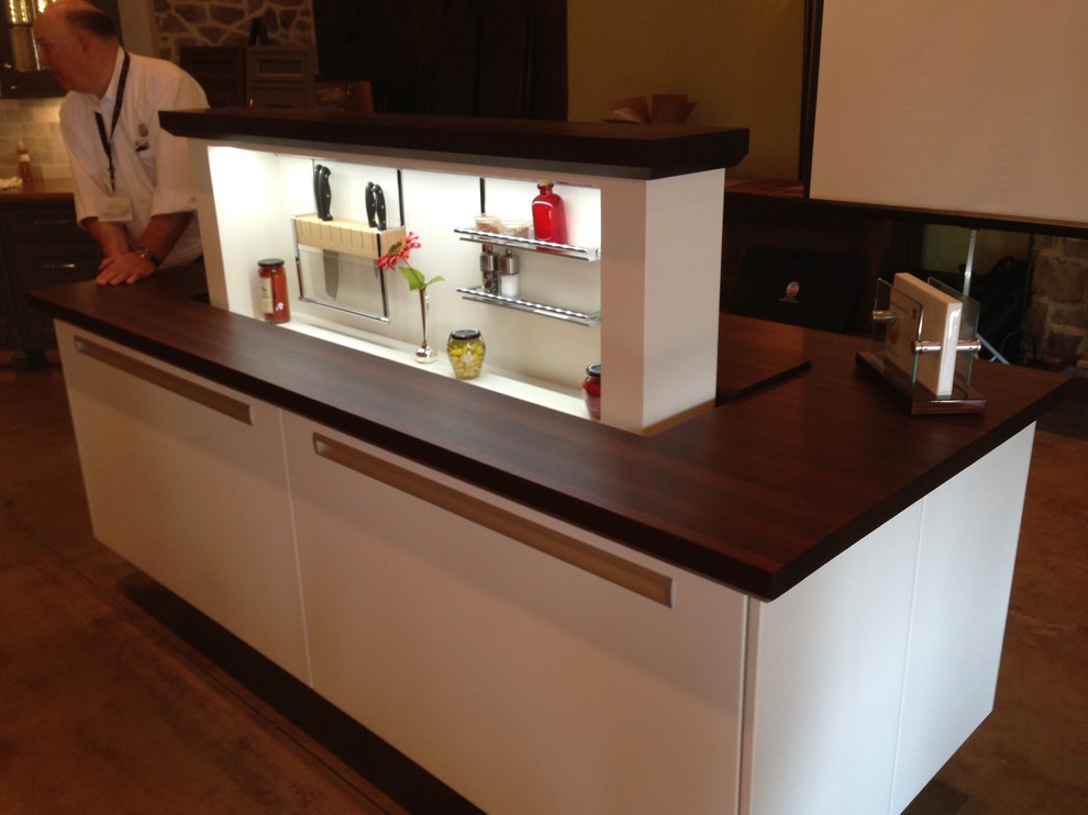 Modelo de cocina contemporánea con armarios con paneles lisos, puertas de armario blancas, encimera de madera y una isla