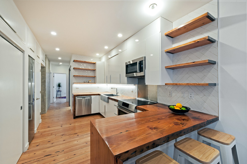 Exempel på ett mellanstort modernt linjärt kök och matrum, med en rustik diskho, släta luckor, vita skåp, träbänkskiva, vitt stänkskydd, stänkskydd i keramik, rostfria vitvaror, mellanmörkt trägolv och en halv köksö