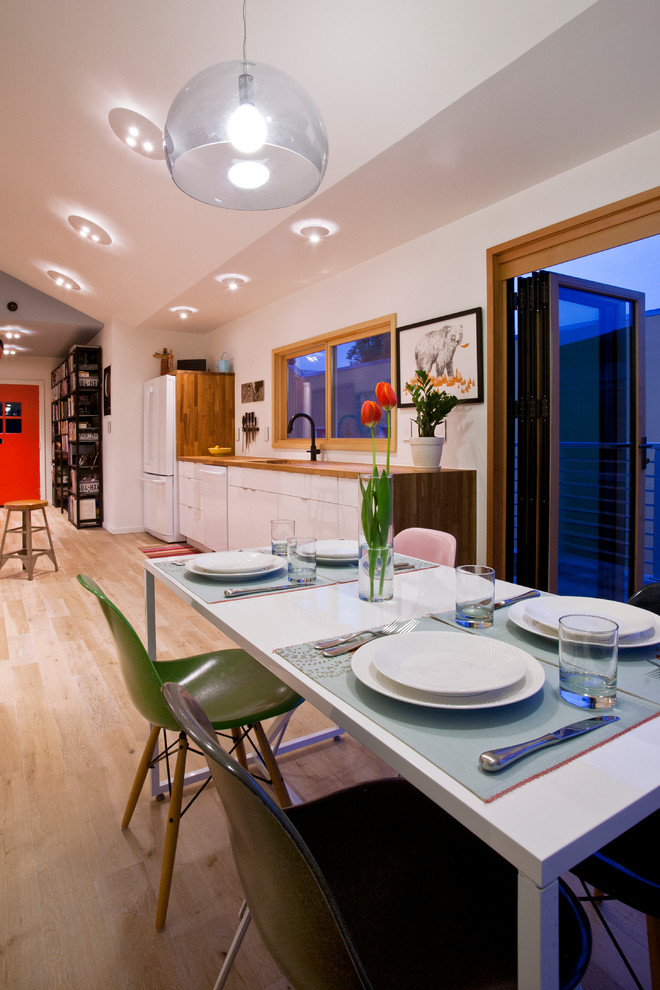 Photo of a medium sized contemporary single-wall kitchen/diner in San Francisco with light hardwood flooring, a built-in sink, flat-panel cabinets, white cabinets and wood worktops.