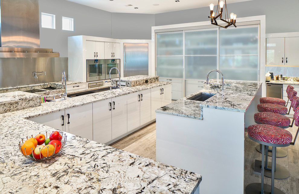 Photo of an expansive contemporary kitchen in Charleston with a triple-bowl sink, flat-panel cabinets, beige cabinets, granite worktops, beige splashback, stainless steel appliances, porcelain flooring and an island.