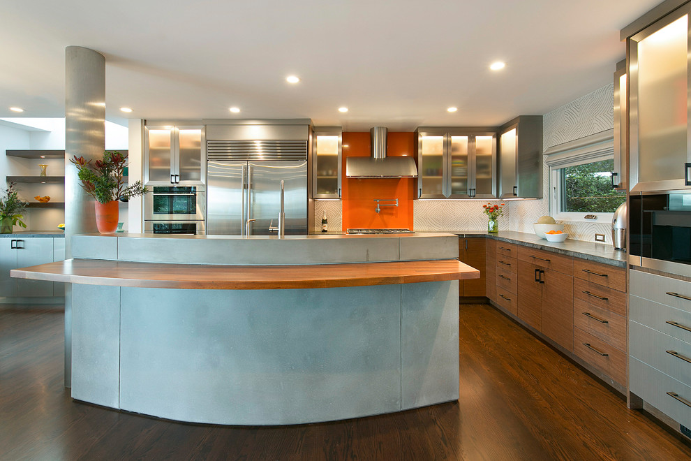 サンフランシスコにある高級な広いコンテンポラリースタイルのおしゃれなキッチン (フラットパネル扉のキャビネット、中間色木目調キャビネット、白いキッチンパネル、シルバーの調理設備、濃色無垢フローリング、茶色い床、グレーのキッチンカウンター、シングルシンク、人工大理石カウンター、セメントタイルのキッチンパネル) の写真