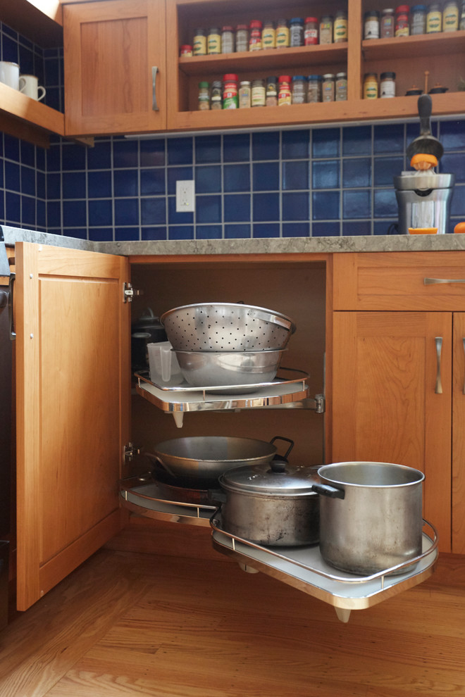 Exempel på ett avskilt, stort klassiskt grå grått l-kök, med en undermonterad diskho, skåp i shakerstil, skåp i mellenmörkt trä, bänkskiva i glas, blått stänkskydd, stänkskydd i keramik, rostfria vitvaror, ljust trägolv och brunt golv