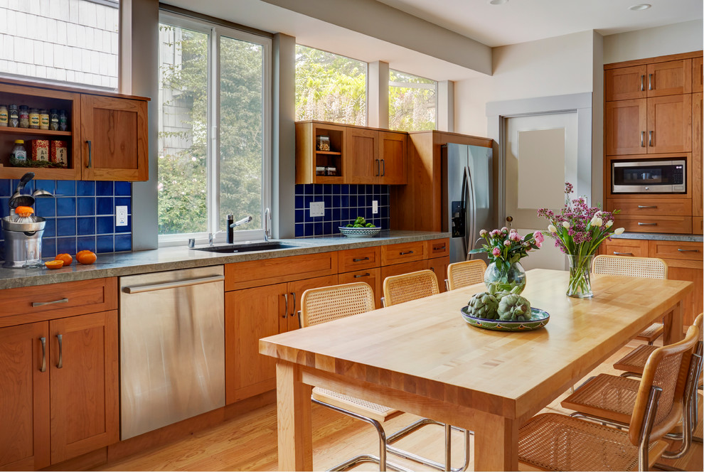 Idées déco pour une grande cuisine classique en L et bois brun fermée avec un évier encastré, un placard à porte shaker, un plan de travail en verre, une crédence bleue, une crédence en céramique, un électroménager en acier inoxydable, parquet clair, aucun îlot, un sol marron et un plan de travail gris.