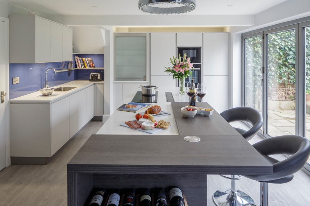 Moderne Wohnküche mit grauen Schränken, Quarzit-Arbeitsplatte, Küchenrückwand in Blau, Glasrückwand und Kücheninsel in Berkshire