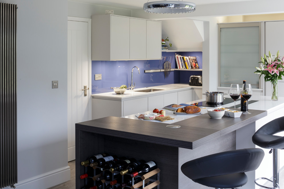 Imagen de cocina comedor contemporánea con puertas de armario grises, encimera de cuarcita, salpicadero azul, salpicadero de vidrio templado y una isla