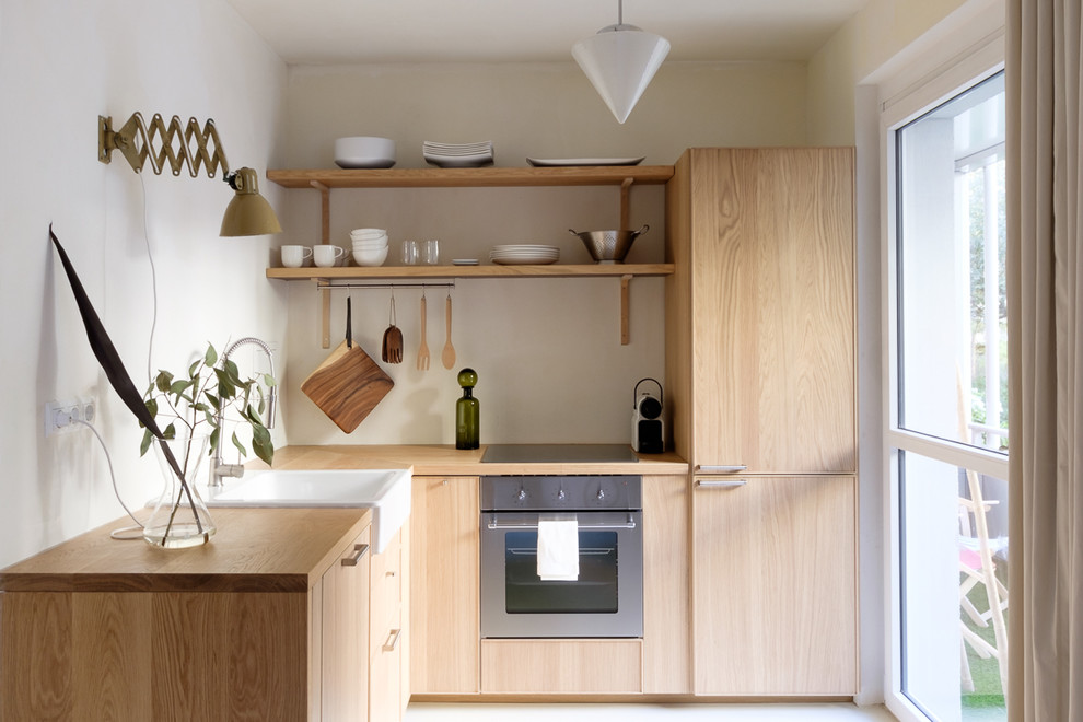 Cette photo montre une petite cuisine ouverte scandinave en L et bois brun avec un évier intégré, un plan de travail en bois, un électroménager en acier inoxydable, aucun îlot et un sol blanc.